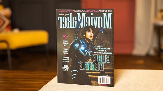 桌上放着一本《菠菜台子大全》杂志. 封面上是一个穿着蓝色甲壳虫服装的演员. 标题是“25所最佳电影学院” & “最酷的电影节”横贯顶部.